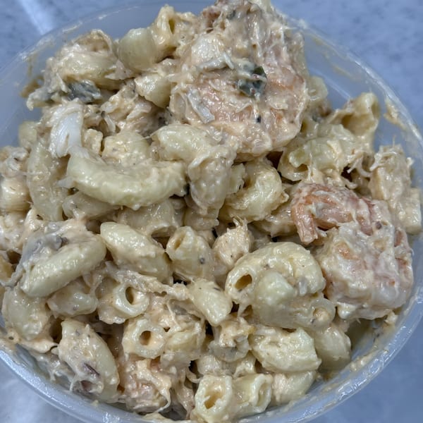 Close-up of Bob's Famous BBQ creamy macaroni salad with shrimp and crab in a clear container.