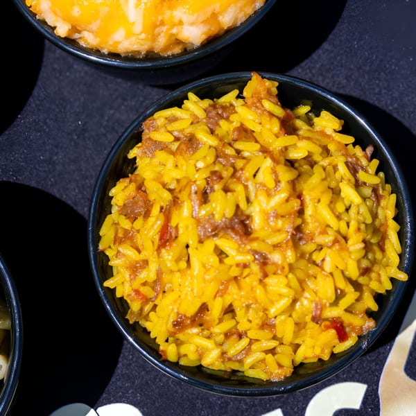 Close-up of a black bowl filled with yellow rice and shredded meat, a Bob's Famous BBQ side.