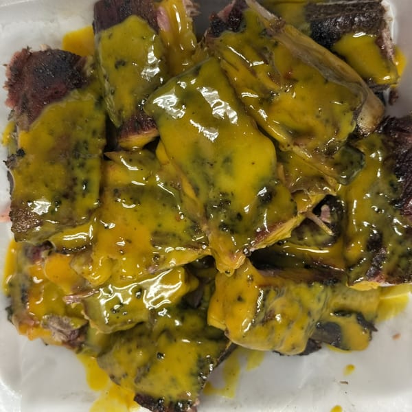 Close-up of Bob's Famous BBQ ribs covered in a vibrant yellow, tangy sauce.