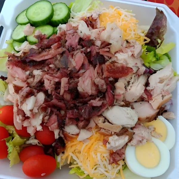 Bob's Famous BBQ salad with smoked meat, chicken, cucumbers, tomatoes, cheese, and hard-boiled eggs.